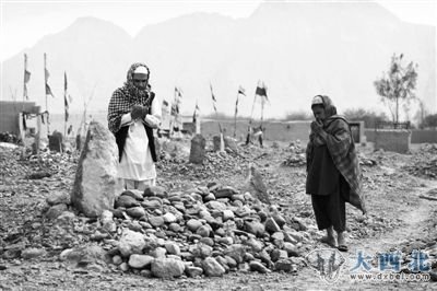 24日,阿富汗坎大哈省,两名当地村民在堆满石块的坟前为枪击案遇害者祈祷。 24日,阿富汗坎大哈省,两名当地村民在堆满石块的坟前为枪击案遇害者祈祷。